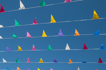 Multicolored, triangular flags against the background of a blue, cloudless sky. - 508820383