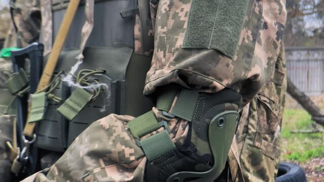 Flag chevron of Ukraine on the shoulder of a soldier in camouflage. The symbol of Ukraine is the state blue-yellow flag on the chevron of an armed soldier of the Ukrainian army.