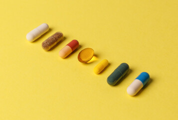 The concept of a healthy lifestyle. Various useful vitamin supplements on a yellow background. Medical pills of different colors. Close-up, side view. Medical preparations. Treatment of diseases.