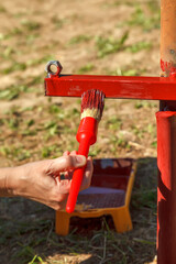Young woman paints red primer metal structure