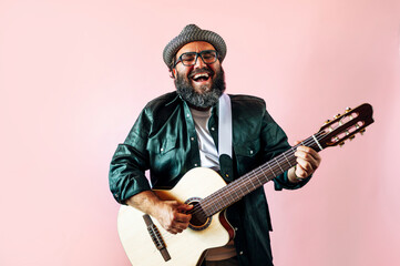 Happy bearded man playing acoustic guitar on pink background. - Powered by Adobe
