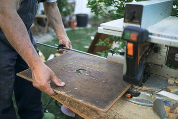 arms gripping a board ready to be cut on a saw.
