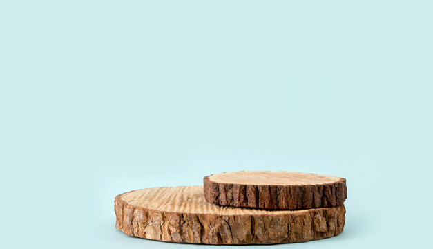 Two pine tree wood discs stacked as a podium for products, blue color background with lot of copy space, studio shot.