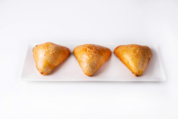three samsa in a white plate on a white background