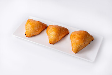 three samsa in a white plate on a white background
