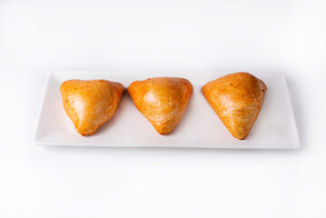 three samsa in a white plate on a white background
