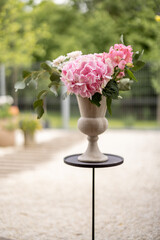 Composition of hydrangea flower with pink blossom in beautiful vase on table in garden