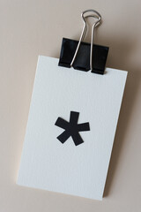 metal clip with postcards and a big black asterisk