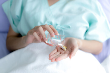 Obraz na płótnie Canvas Hand taking pills to treat sickness at the hospital.