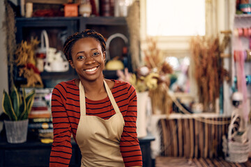 Happy African American woman working as florist at flower shop and looking at camera. - Powered by Adobe