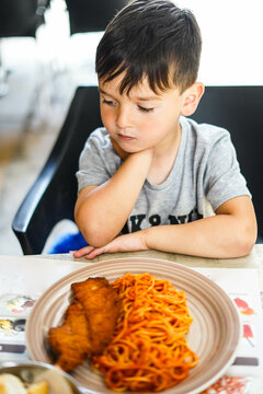 Un ni&ntilde;o comiendo macarrones con escalopa