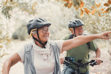 Two happy old mature people enjoying and riding bikes together to be fit and healthy outdoors....