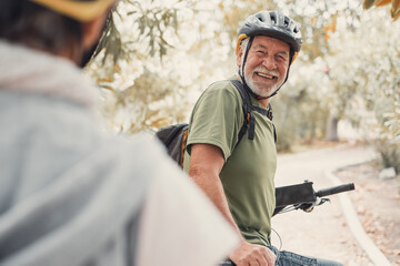 Two happy old mature people enjoying and riding bikes together to be fit and healthy outdoors. Active seniors having fun training in nature. Portrait of one old man smiling in a bike trip with wife - Powered by Adobe
