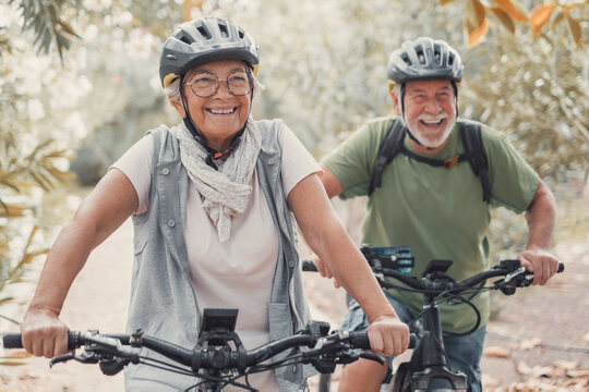 Two happy old mature people enjoying and riding bikes together to be fit and healthy outdoors. Active seniors having fun training in nature.