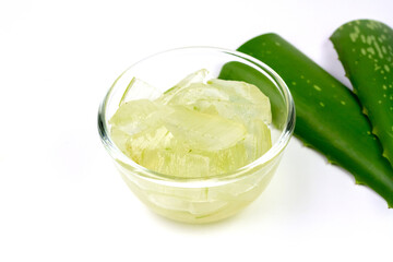 Aloe vera gel in transparent glass bowl with fresh aloe vera isolated on white background.