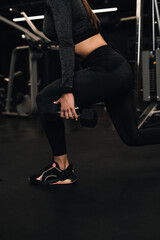 Fototapeta na wymiar girl athlete doing squats with dumbbells in the gym. dark background