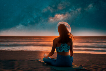 silhouette of a woman on the shore of the beach meditating at night with the moon and milky way in...