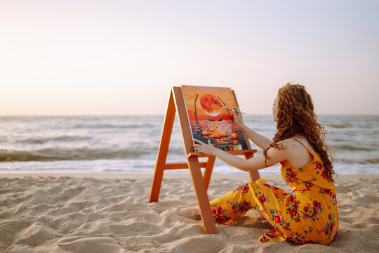 Young female artist drawing the picture at the beach. Hobby and leisure concept. Talent and creativity. Canvas Painting.