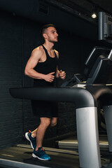 guy athlete runs on a treadmill in the gym. dark background