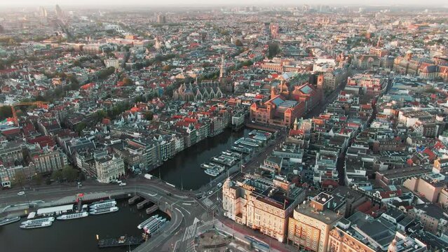 Aerial Drone Shot of the famous houses lining the edge of the Damrak canal basin, Amsterdam, Netherlands in the early morning