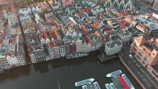 Aerial Drone Shot of the famous houses lining the edge of the Damrak canal basin, Amsterdam, Netherlands in the early morning