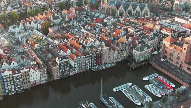 Drone Shot of the famous houses lining the edge of the Damrak canal basin, Amsterdam, Netherlands in the early morning