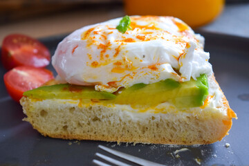 Poached Benedict Egg on a Toast with Avocado and Cherry Tomatoes.