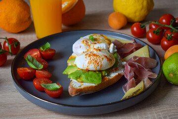 Poached Benedict Egg on a Toast with Avocado and Cherry Tomatoes.