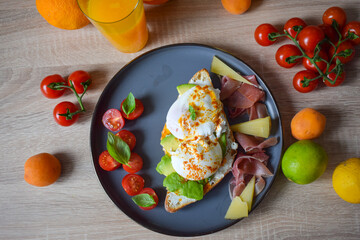 Poached Benedict Egg on a slice of baguette with avocado and cherry tomatoes.