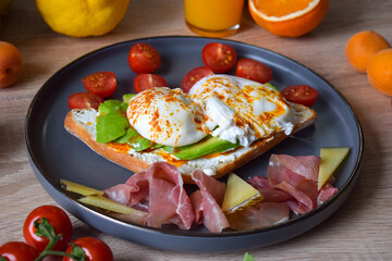 Poached Benedict Egg on a slice of baguette with avocado and cherry tomatoes.
