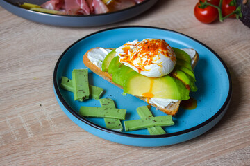 Poached Benedict Egg on a slice of baguette with avocado and cherry tomatoes.