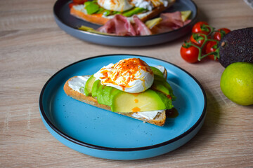 Poached Benedict Egg on a slice of baguette with avocado and cherry tomatoes.