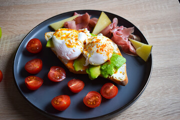 Poached Benedict Egg on a slice of baguette with avocado and cherry tomatoes.