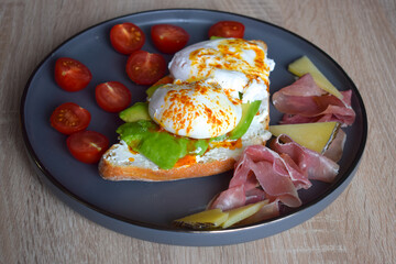 Poached Benedict Egg on a slice of baguette with avocado and cherry tomatoes.