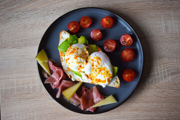 Poached Benedict Egg on a slice of baguette with avocado and cherry tomatoes.