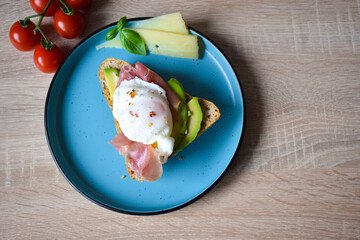 Poached Benedict Egg on a slice of baguette with avocado and cherry tomatoes.