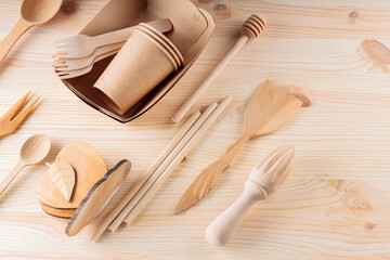 Various kitchen utensils on a wooden table. Set of the wooden cutlery and biodegradable carton paper cups. Eco-friendly sustainable lifestyle. Zero waste, plastic free concept