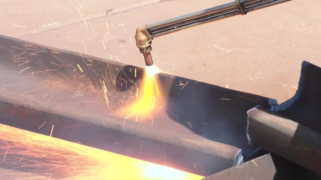 Welder using cutting torch to cut a rail.  Close-up of the hand of an industrial worker working on the process of cutting rails.
