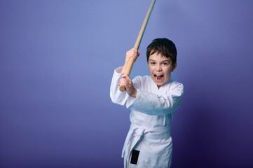 Portrait of a child boy aikido wrestler wearing traditional samurai hakama kimono learning fight...