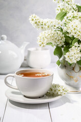Useful spring tea with bird cherry in a white cup on a light background