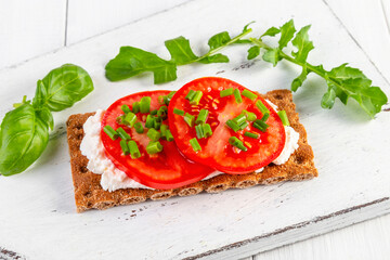 Crispbread with curd cheese, tomatoes, green onions, arugula and basilica. Delicious and healthy breakfast