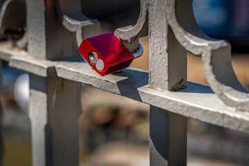 ein einzelnes rotes Liebesschloss an den Ornamenten eines alten Brückengeländers befestigt