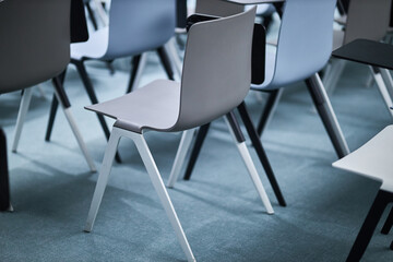 modern gray plastic office chairs. Several rows of empty plastic chairs in the audience prepared for the speaker's speech in front of students or journalists and spectators. 
