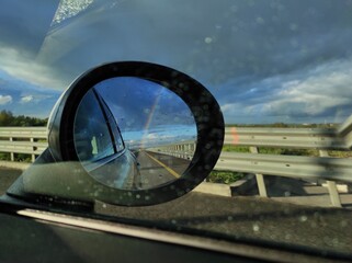 Fototapeta na wymiar rainbow in the reflection of a car mirror on the road