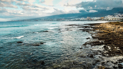 Fototapeta premium View of dramatic coast with rocks and blue ocean water. Sky with clouds at the horizon. Concept of touristic place for holiday vacation. Scenic destination in Tenerife