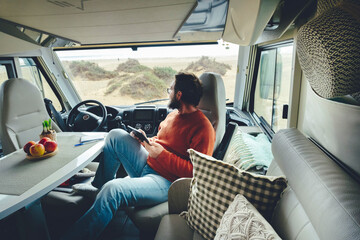 Adult man relaxing after trip with camper van parked free with beach view. Planning travel destination people with motor home vehicle. Concept of alternative lifestyle and home.  Modern male life