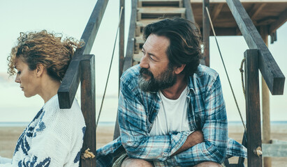 Couple problems and divorce concept with serious and sad man and woman outdoors separated. Wife and husband sitting together looking in different directions. End of relationship for couple