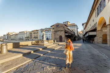 Woman walking on famous old bridge, called Ponte Vecchio, in Florence. Concept of traveling italian...