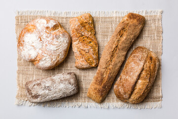 Assortment of freshly baked bread with napkin on rustic table top view. Healthy unleavened bread. French bread