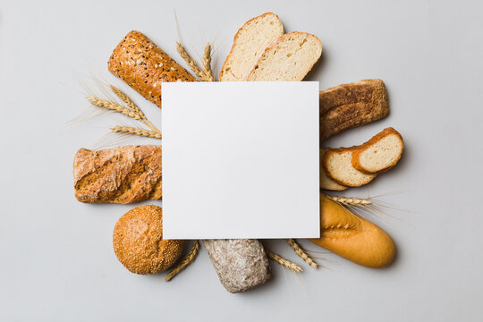 Minimalist paper blank mockup on background of Types of homemade bread. Different kinds of fresh bread as background, top view with space for your text or design